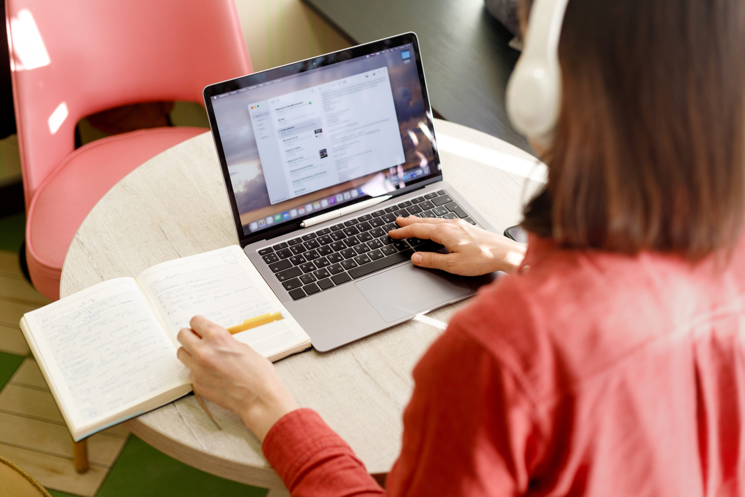 beautiful caucasian millennial woman talking on the phone and working on her laptop in home office, watching a webinar or chatting with friends on a webcam, online education and work, online shopping